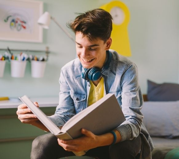 teen boy reading in room